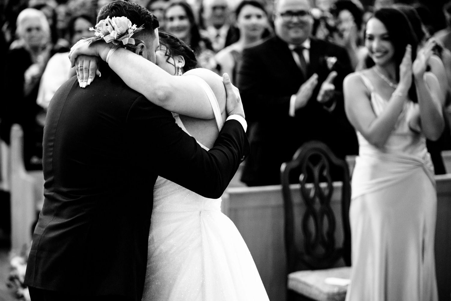 A couple shares their first dance at a wedding reception while guests look on and capture photos.