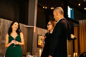 People in formal attire gather at an elegant evening event with ambient lighting and cocktails.