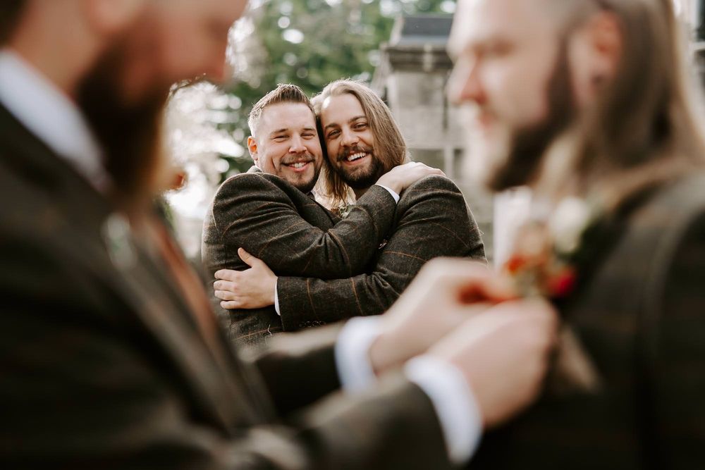 Two people embrace in a joyful hug while celebrating at an outdoor wedding ceremony.