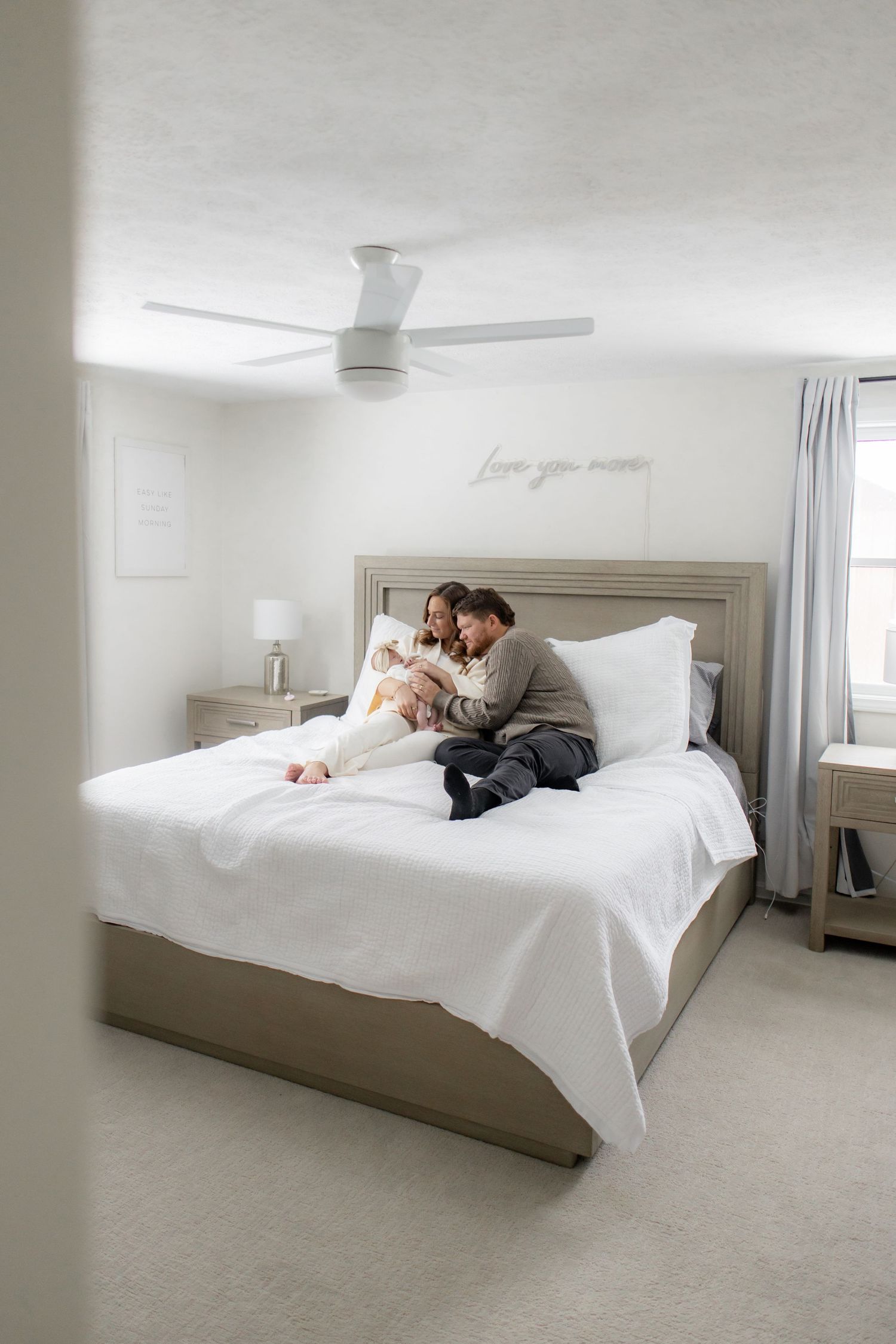 A couple lying together on a white bed in a minimalist bedroom setting, showing progression of movement across frames.