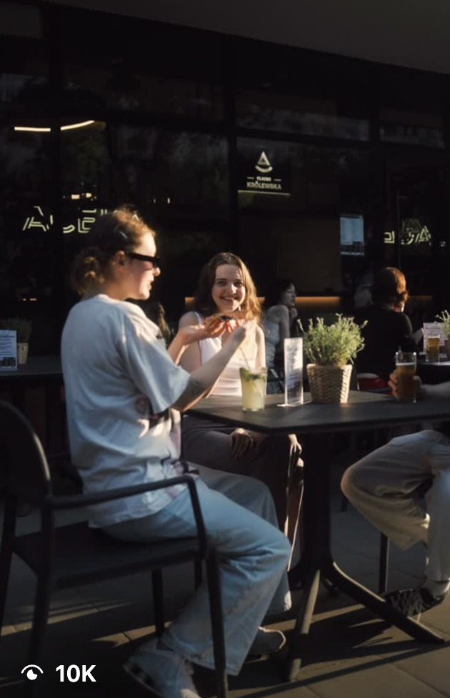 Person sitting at a dimly lit restaurant table using a mobile phone in casual attire.