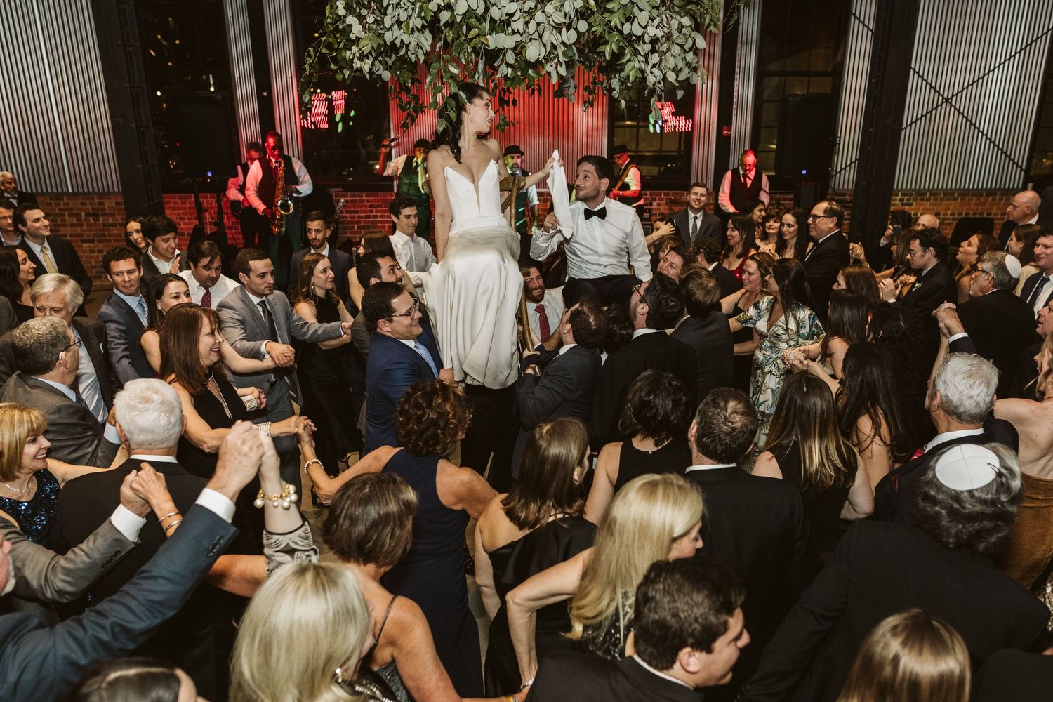 Wedding guests dance and celebrate on a crowded dance floor during an evening reception. Kehoe Iron Works savannah industrial wedding venue