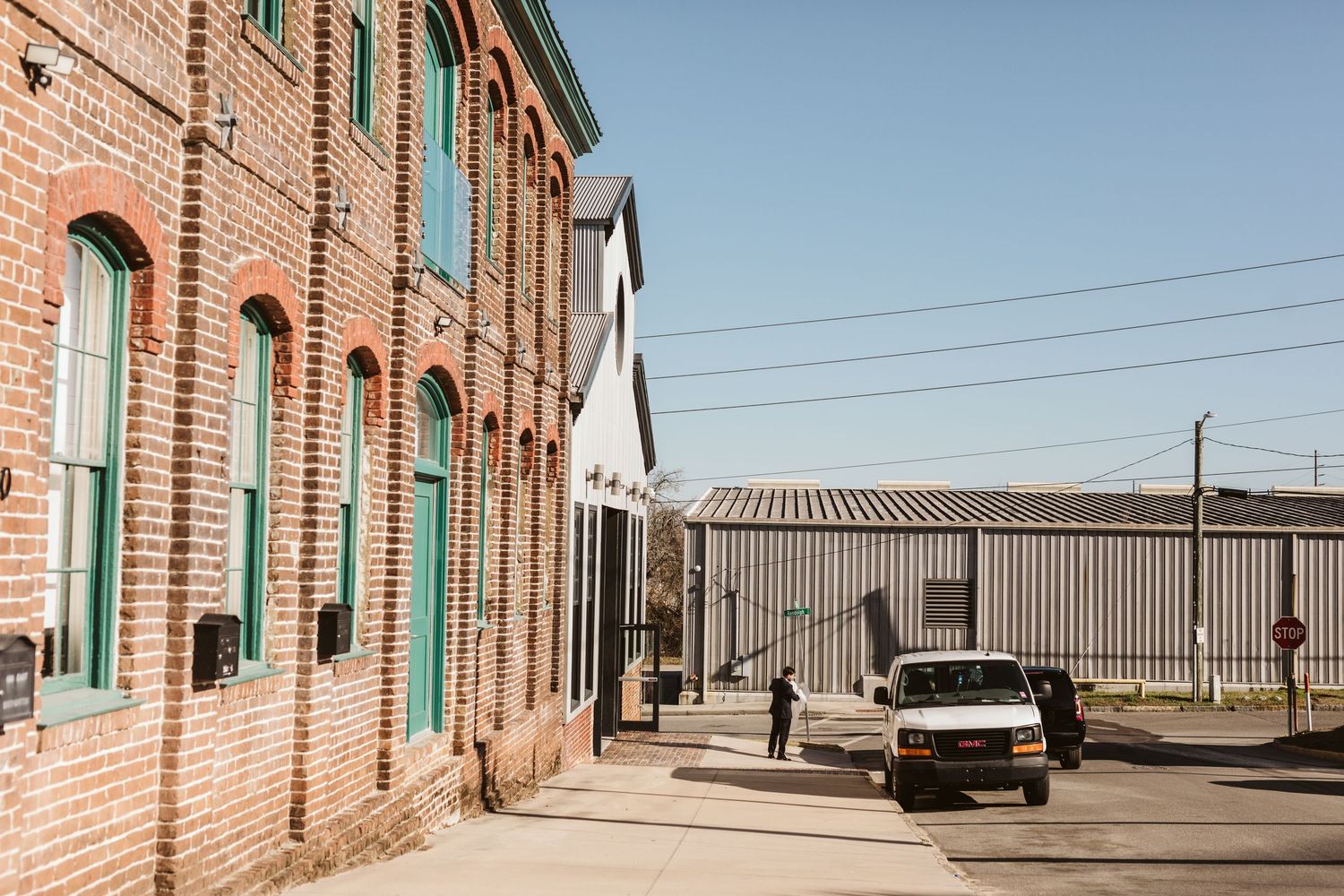 Exterior view of a historic brick building with green shuttered windows and industrial warehouse architecture. Kehoe Iron Works, Savannah GA