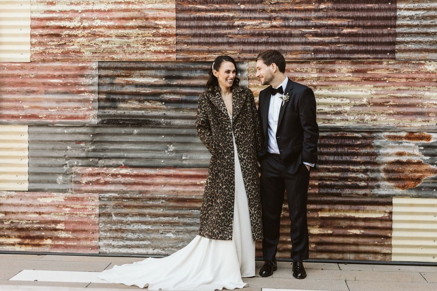 A couple poses against a rustic corrugated metal wall during their wedding photoshoot. Kehoe Iron Works, Savannah GA Wedding Venue