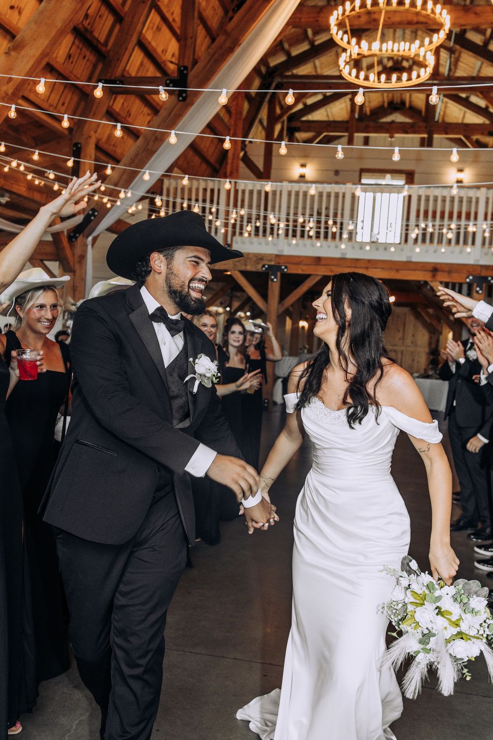 Joyful bride and groom share a moment during their grand entrance at a barn wedding.