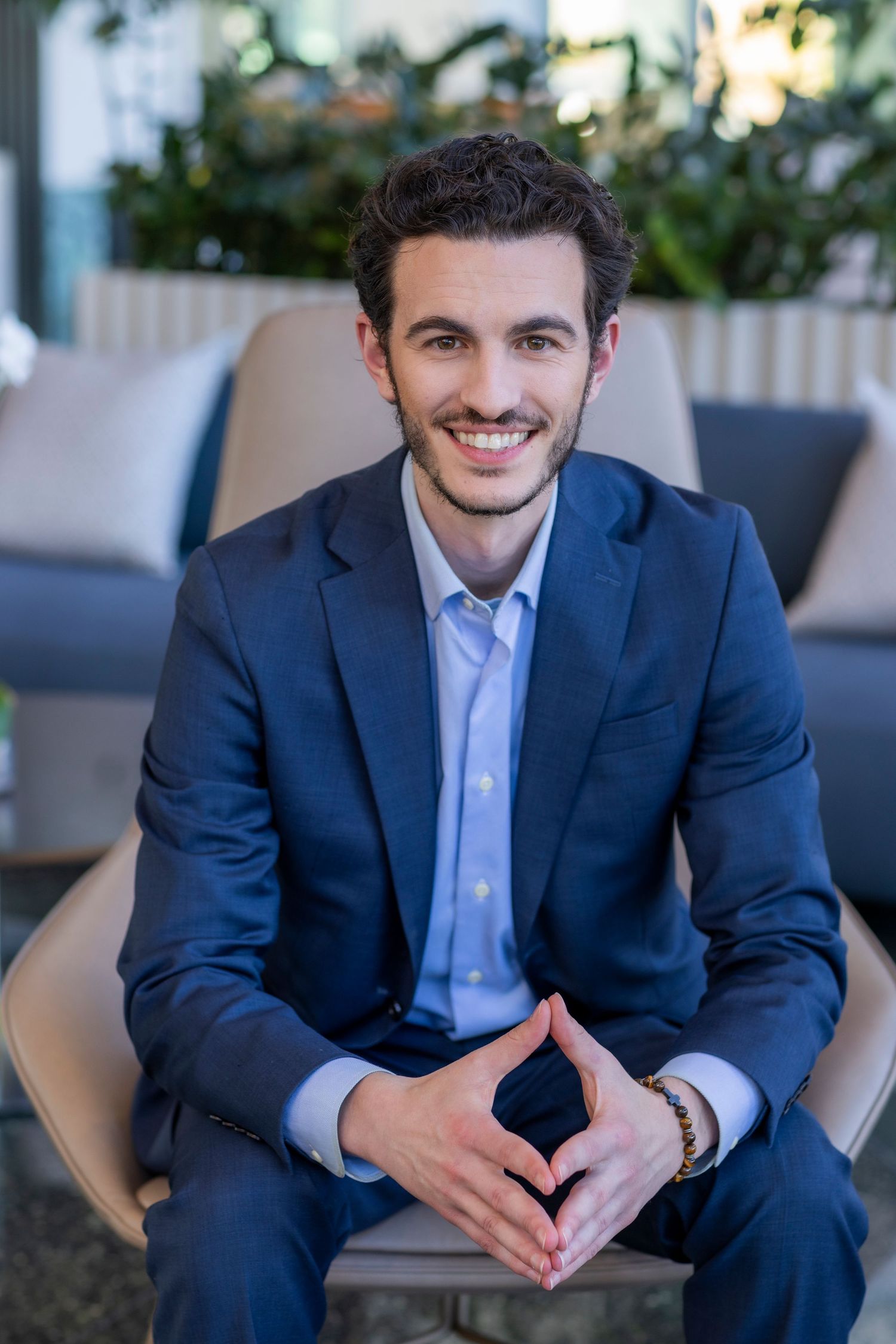 Professional in a navy suit and light blue shirt poses for a series of headshots in a modern office setting.