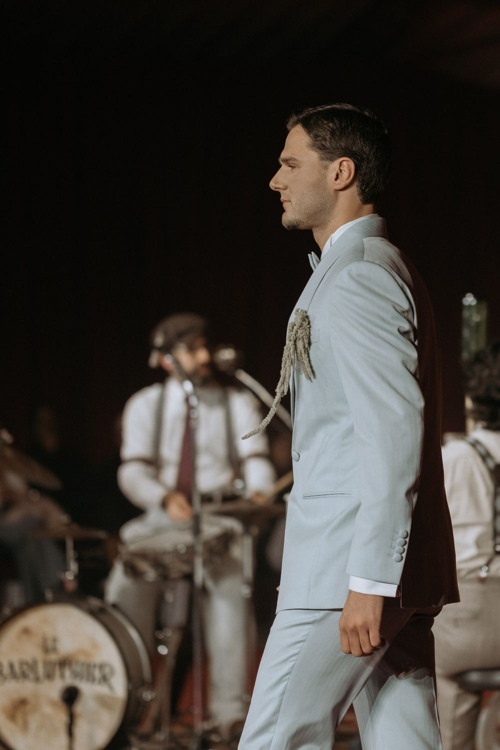 Vintage black and white photo of musicians performing in white uniforms with a drum set visible in the background.