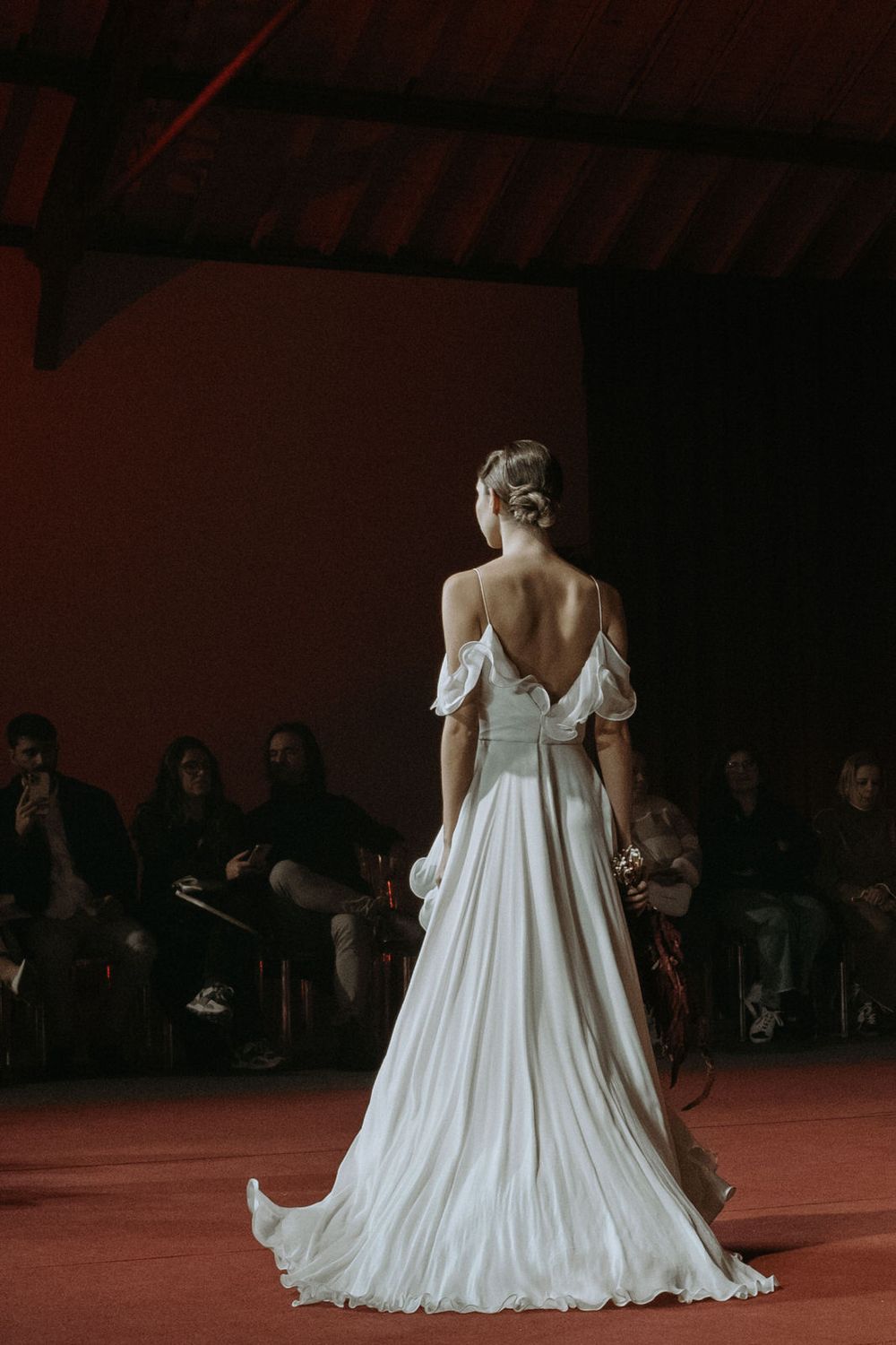 A series of photos showing a flowing white wedding dress on a dark stage with audience members visible in the background.