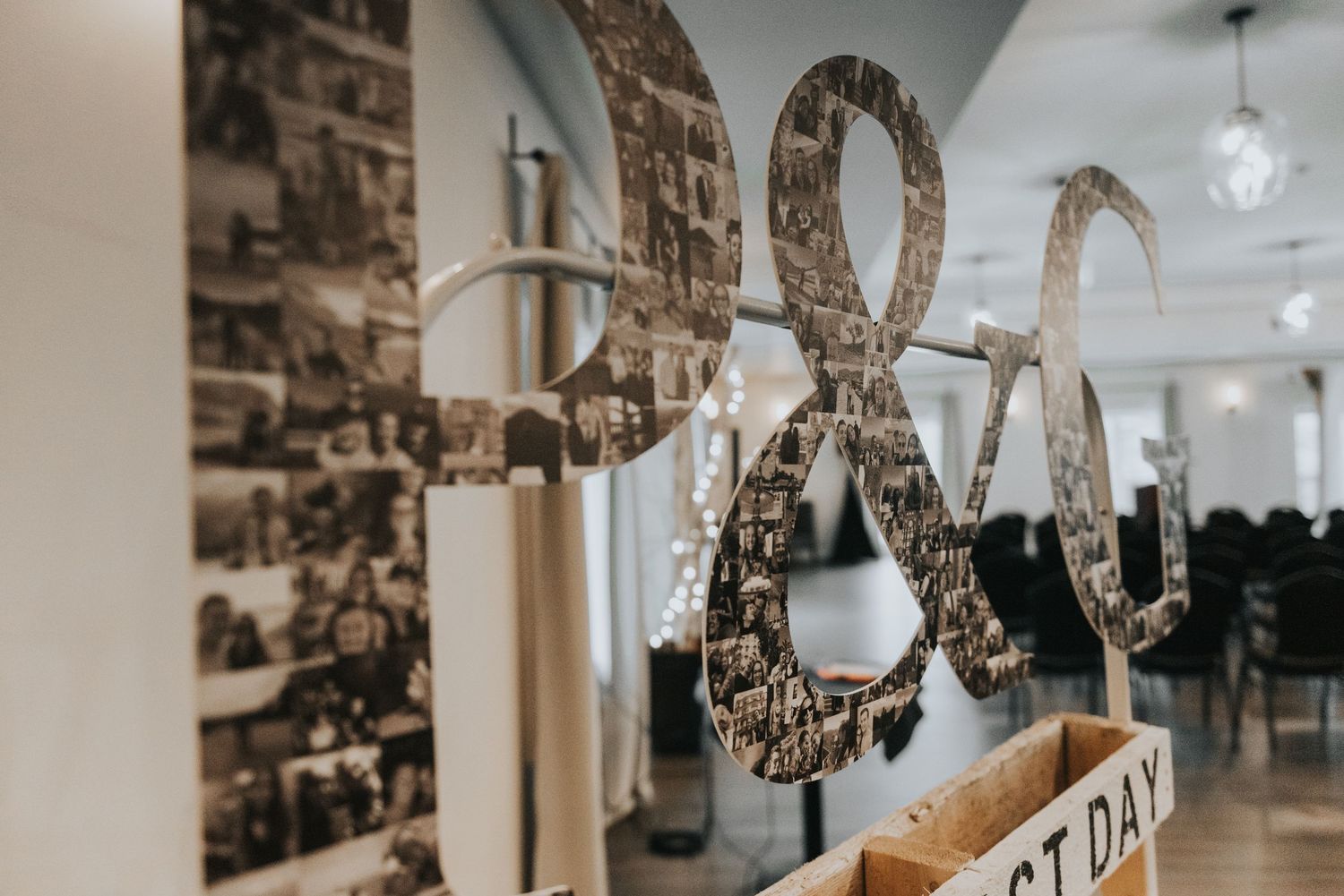 Decorative ampersand wall art with black and white photo collage wallpaper in modern interior space.