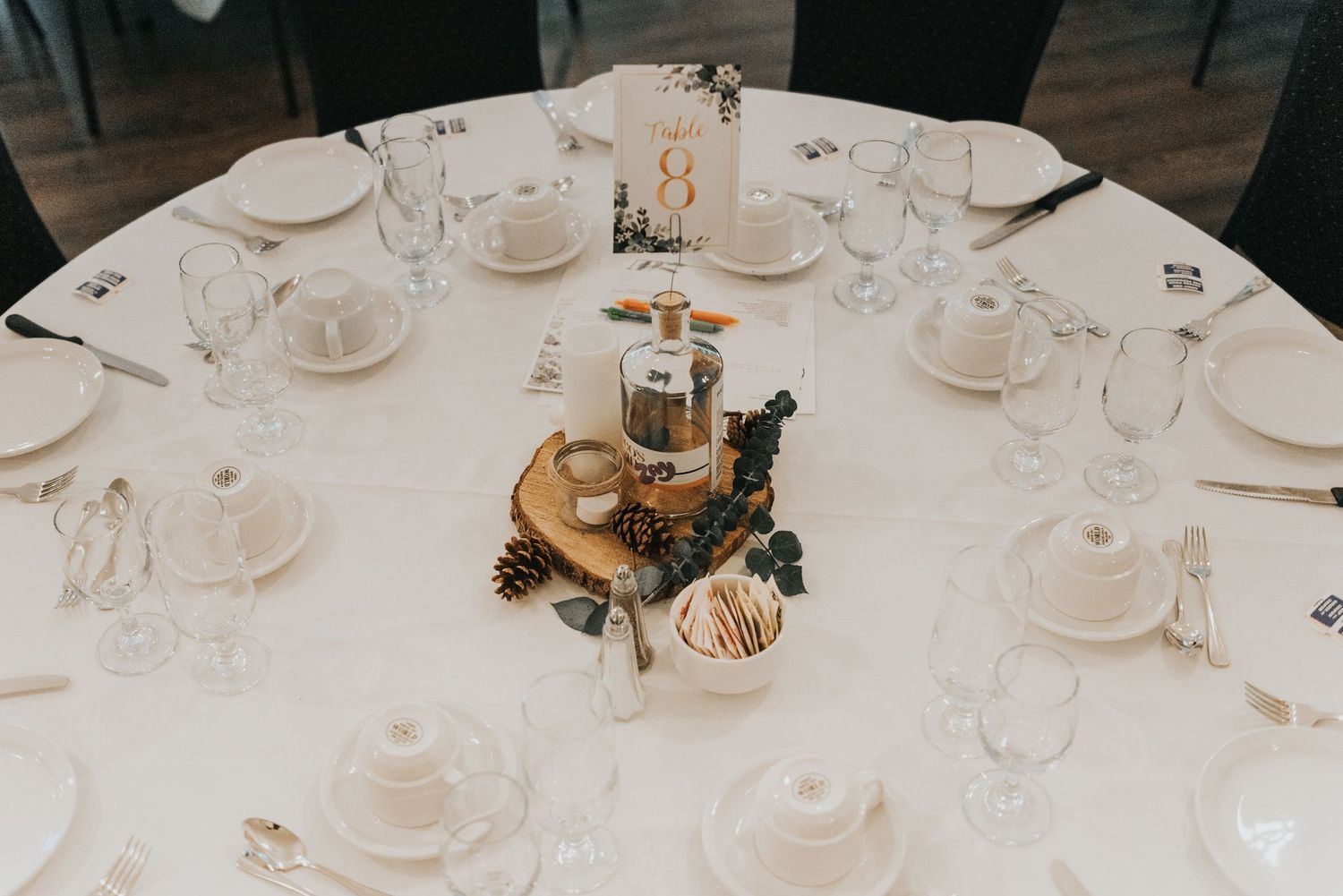 White place settings and wine glasses arranged on elegant dining tables for an upscale event or wedding reception.
