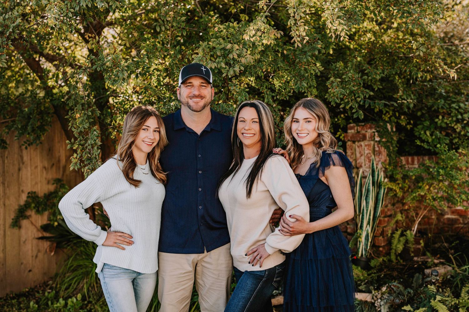 Group portrait taken outdoors with natural greenery and trees in the background.