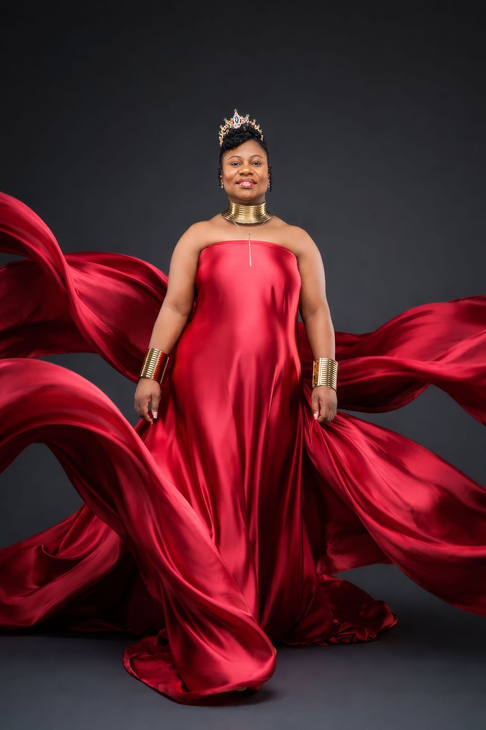 A dramatic fashion photo series showing flowing red satin gown against dark background with billowing fabric movement.