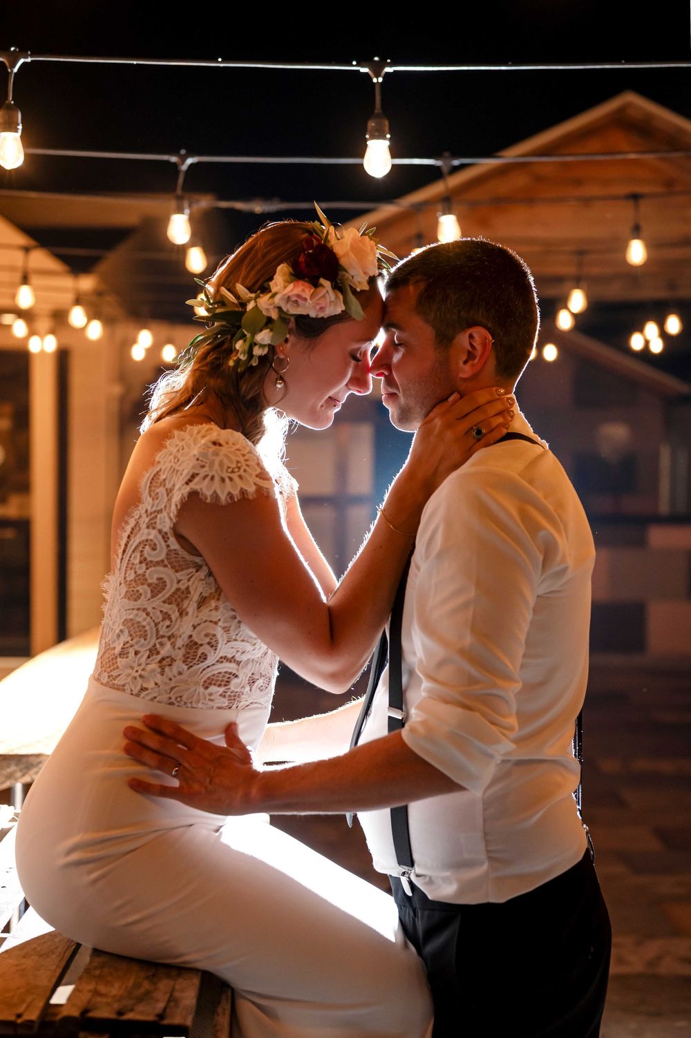 Intimate wedding dance under string lights in rustic venue.