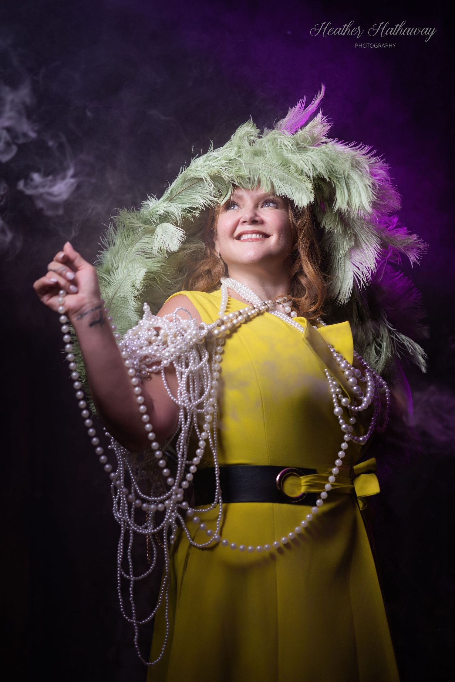 A figure in a bright yellow dress with feathered green hat and pearl necklaces poses dramatically against a dark background.