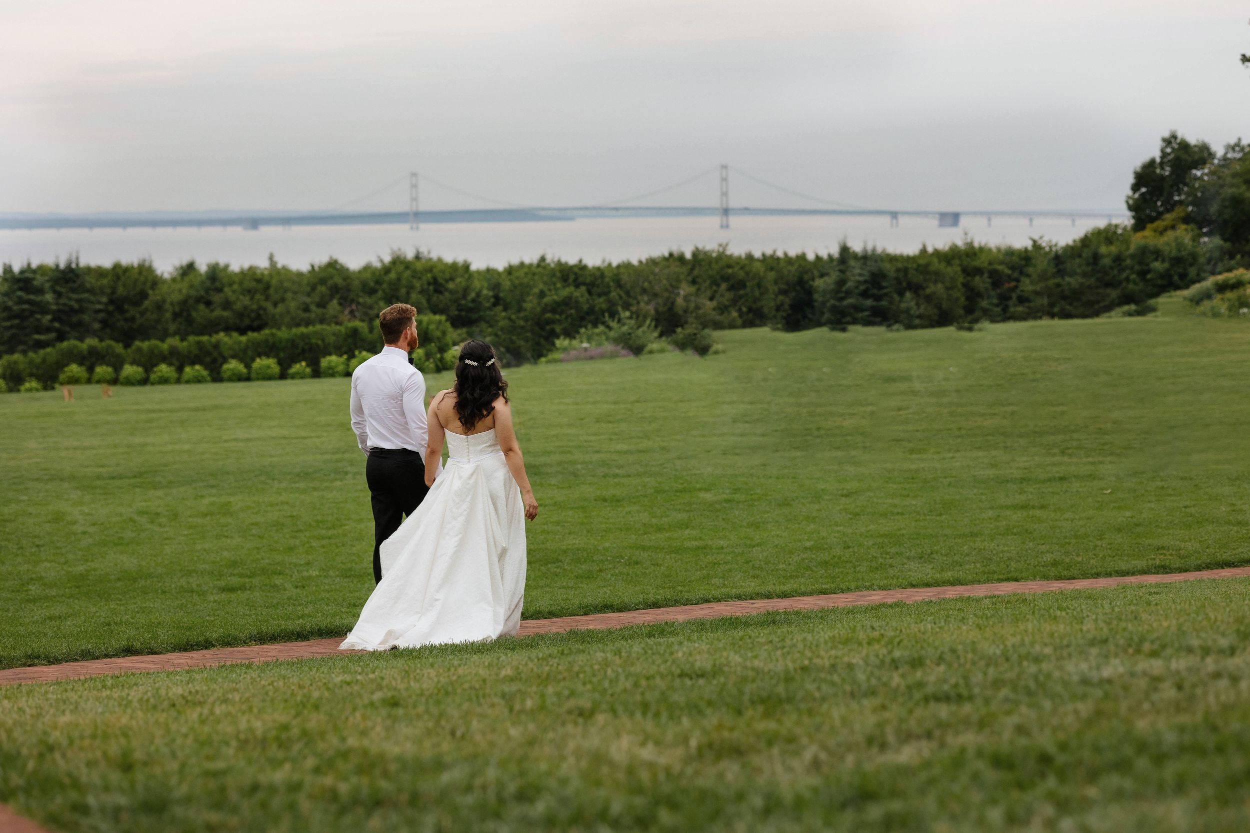 Panoramic view of a lush green field with rolling hills on a cloudy wedding day.