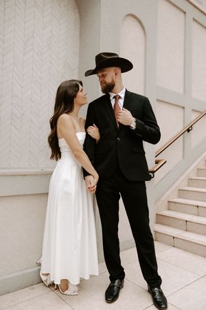 A couple in formal wear shares intimate dance moments near a staircase.