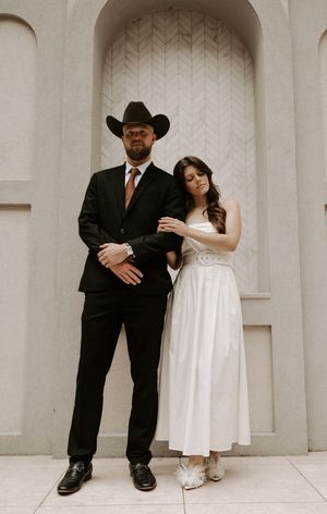 Modern wedding photography with couple posing against architectural backdrop.