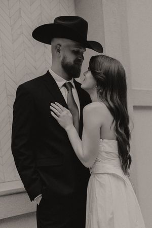 Intimate black and white portrait of couple sharing romantic moment against geometric wall.