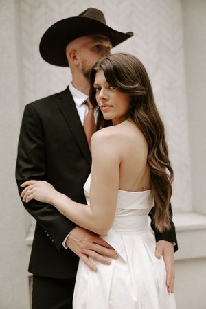 Romantic couple in wedding attire share intimate moments against a light backdrop in a series of artistic photos.