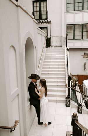Wedding couple poses on elegant white staircase for intimate photo series.