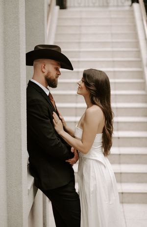 Tender moments between newlyweds captured in black and white against architectural backdrop.
