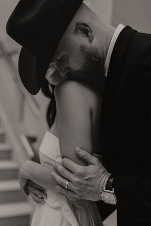 An intimate black and white portrait showing a tender embrace and wedding ring detail.
