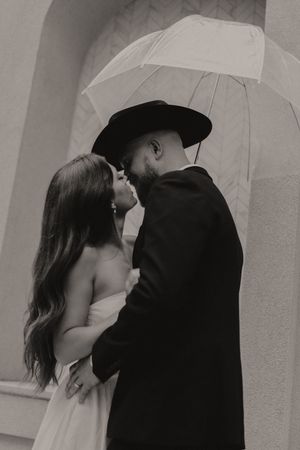 Artistic black and white photo series of a couple sharing romantic moments under a white umbrella.