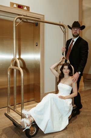 Playful wedding couple poses near an elevator in a modern building.