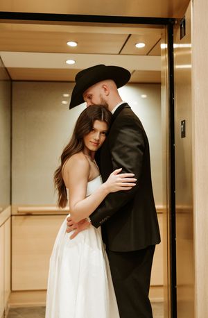 Intimate moments captured between couple in modern building elevator area.