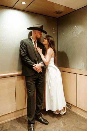 A couple in wedding attire embrace in an elegant indoor setting.