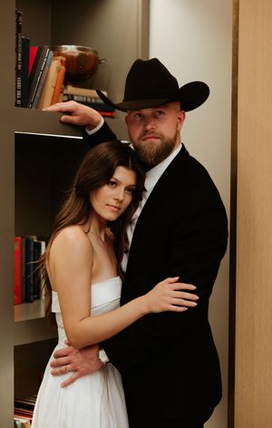 An intimate photoshoot of a couple posing together against built-in bookshelves.