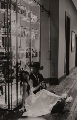 Black and white photo of a couple in formal attire posing near glass display shelves.