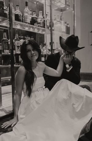 Black and white photograph showing a romantic moment between a couple by glass shelving.