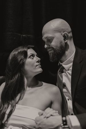 A black and white portrait of a couple in formal attire sharing an intimate moment.