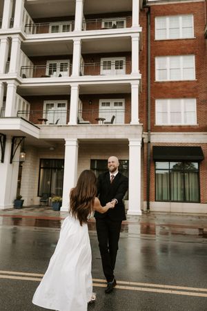 A sequence of candid moments between a couple in white and black formal attire outside a brick building.