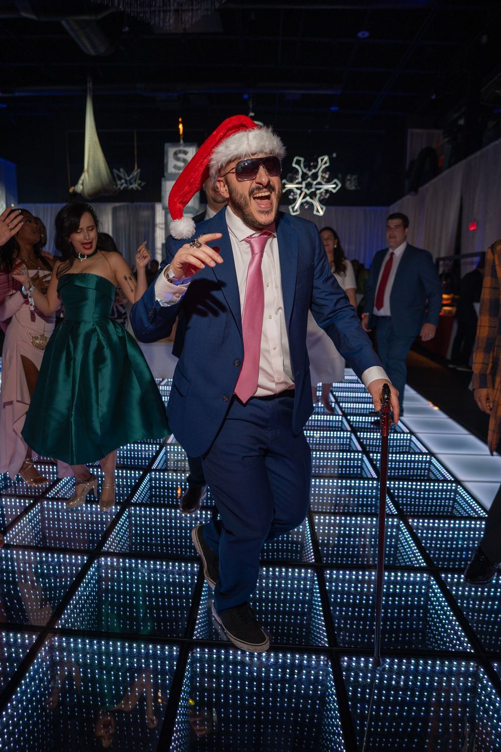 People dancing and celebrating at a wedding reception with illuminated LED dance floor panels.