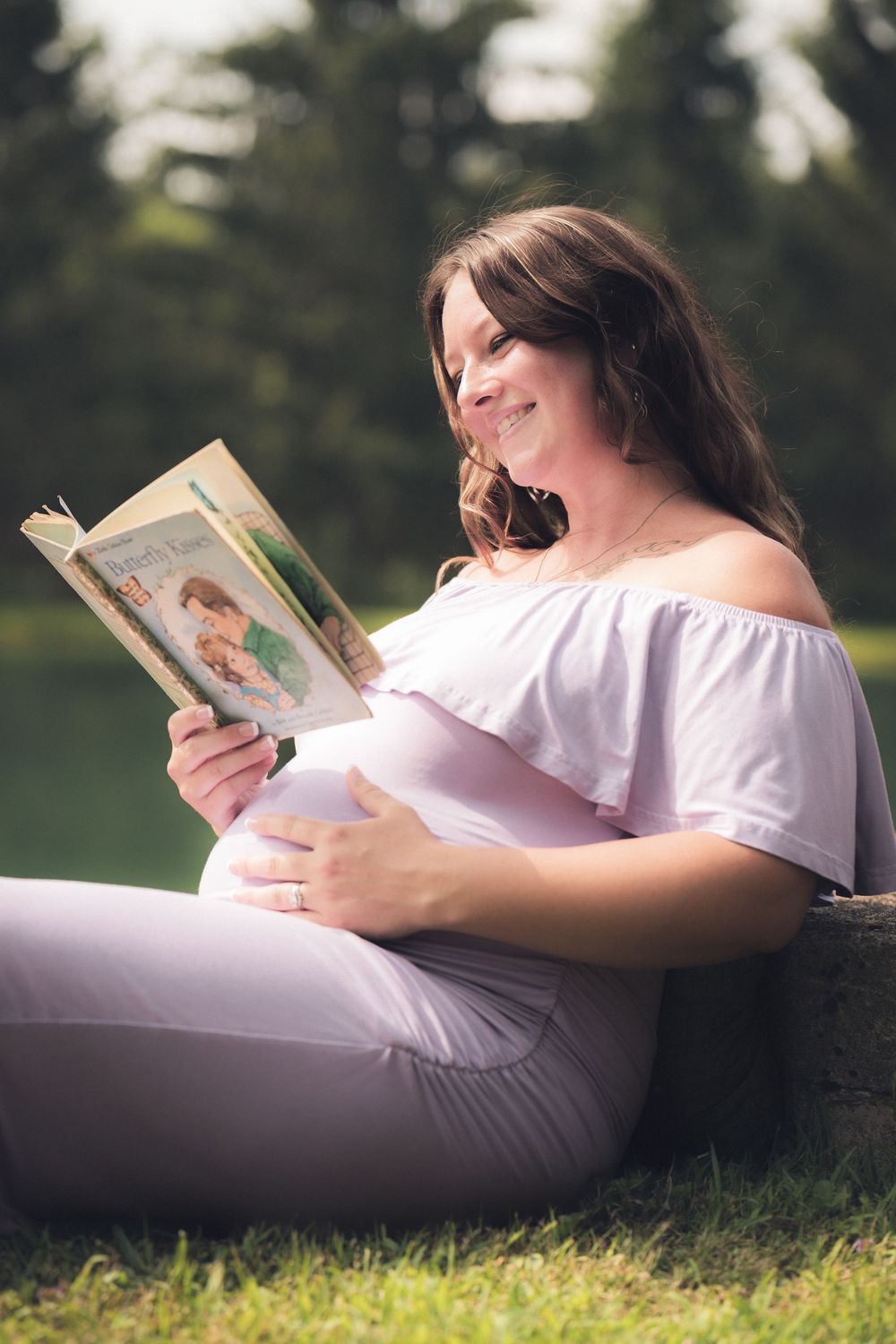 Person relaxing outdoors while reading a book on grassy ground.