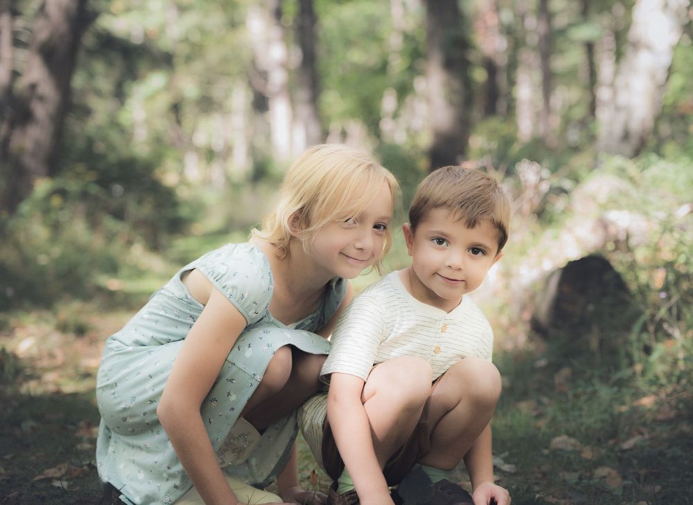 Children playing and exploring together in a sunlit forest setting.