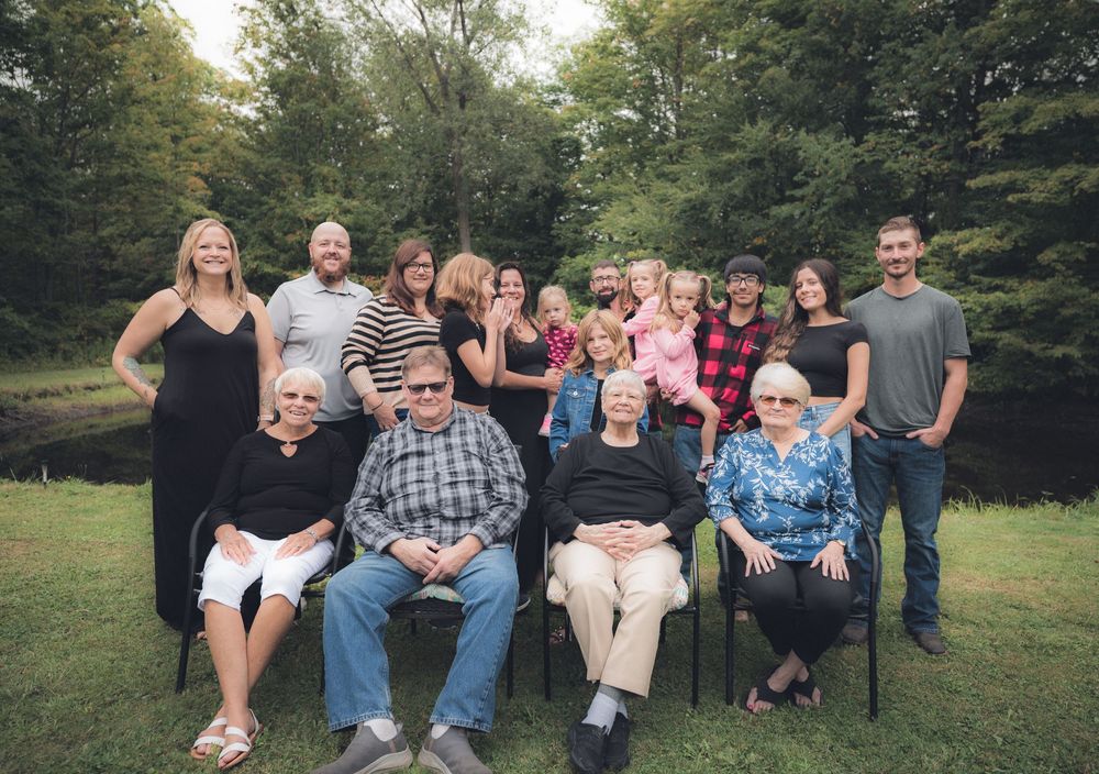 Large family group poses together outdoors for a casual portrait on a sunny day.