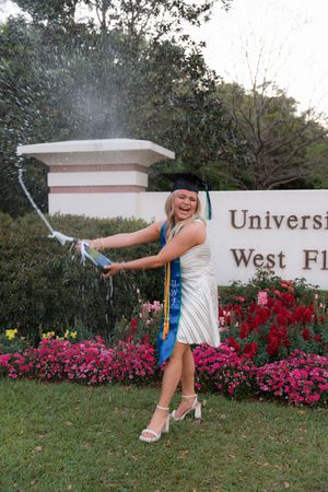 A series of playful poses in front of a university entrance sign with pink flowers blooming in the background.