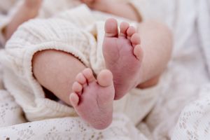 Close-up of adorable newborn baby feet wrapped in a soft white knit blanket, perfect for birth announcements.