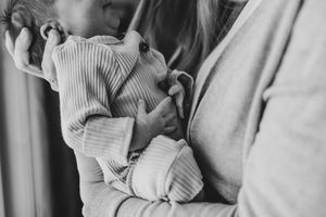 Black and white photo of a mother tenderly cradling her newborn baby in her arms.