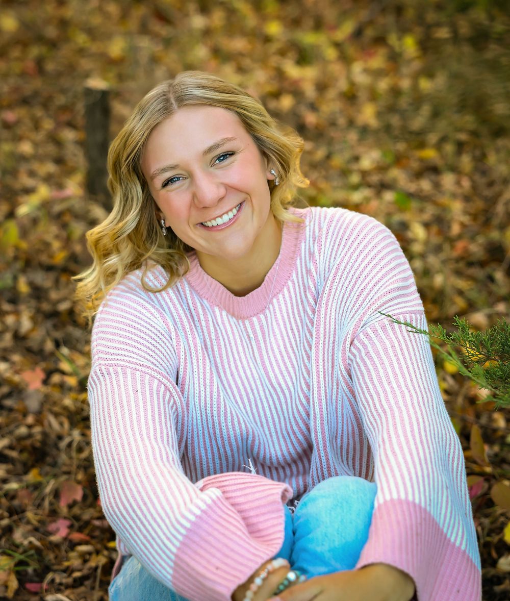Autumn portrait session with striped sweater among fallen leaves.