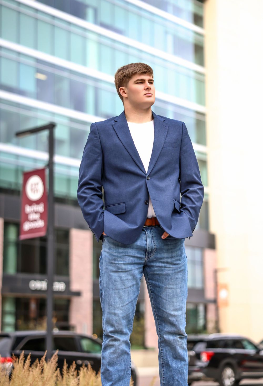Casual business style with navy blazer and jeans in urban setting with storefronts.