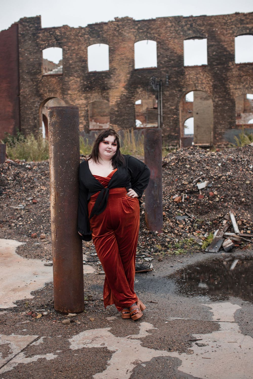 A figure in a red dress poses dramatically against industrial ruins and rubble in a series of connected photos.
