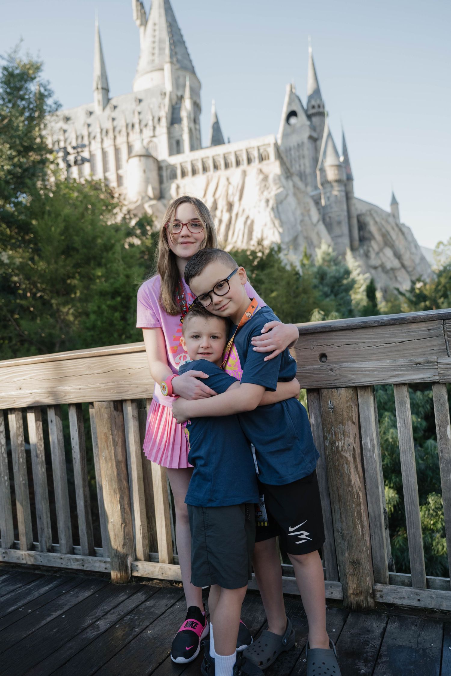 Three siblings hugging and smiling together in front of Hogwarts Castle at Universal Studios Florida.