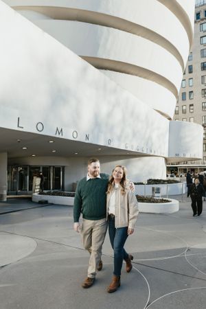 A couple poses in front of the iconic spiral architecture of the Solomon R. Guggenheim Museum in New York City - Engagement Photography