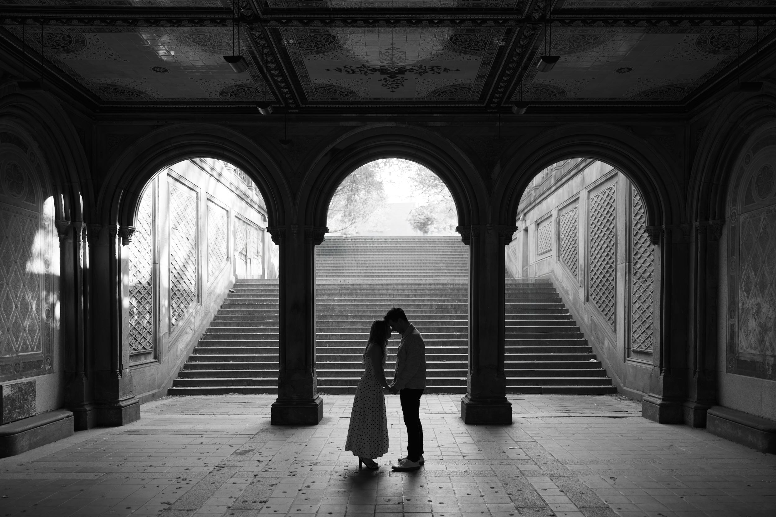 Black and white photo series showing silhouettes of people walking through an archway in Central Park's Bethesda Terrace.