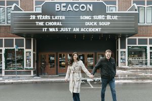 A vintage movie theater marquee displays 'Beacon' and other text on a brick building facade.