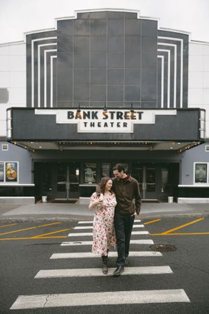A couple walks across a crosswalk in front of the vintage Bank Street Theater with its art deco facade. - Engagment Photo - Hudson Valley